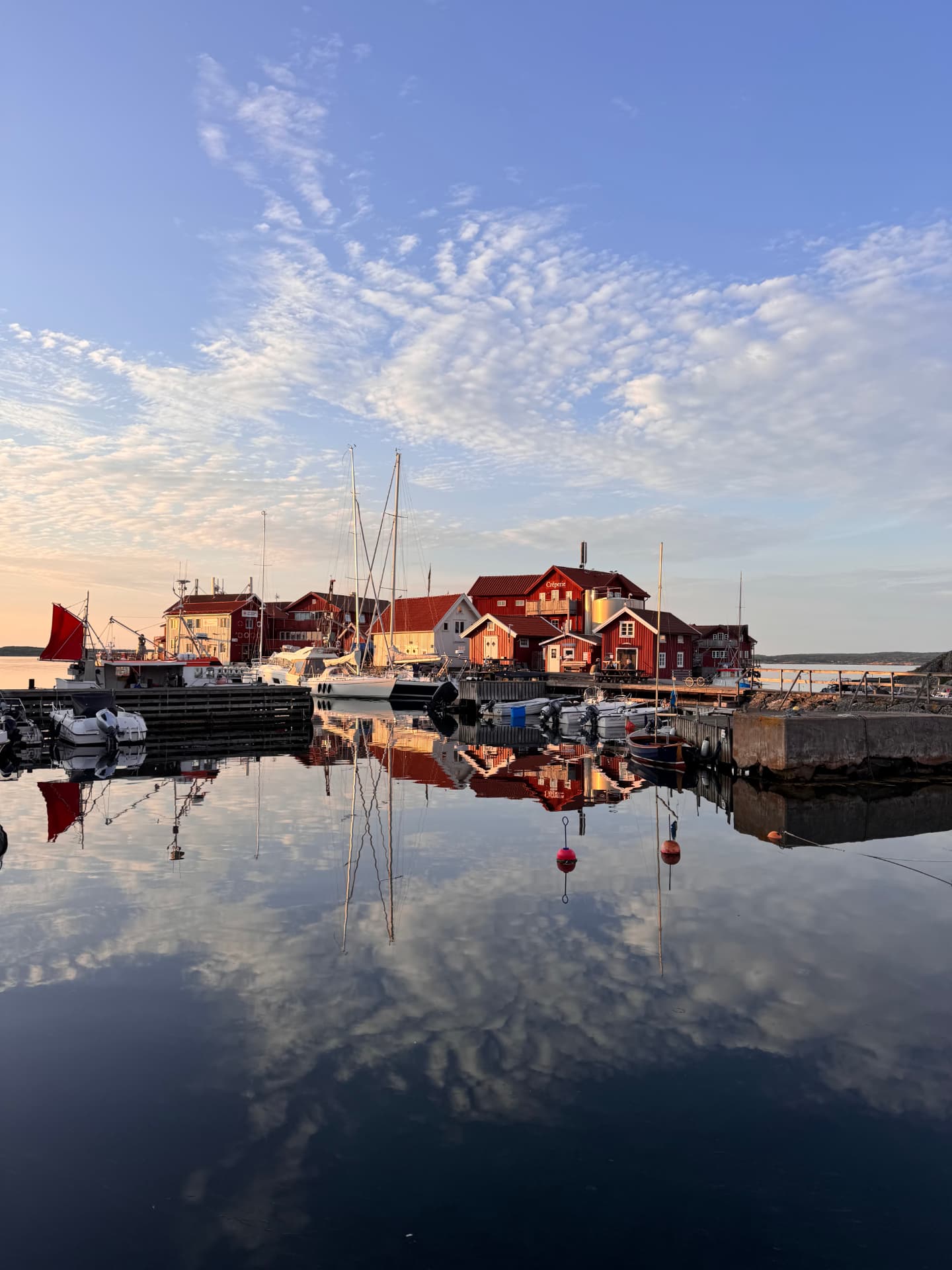 Käringöns hamn med röda sjöbodar och båtar vid bryggan